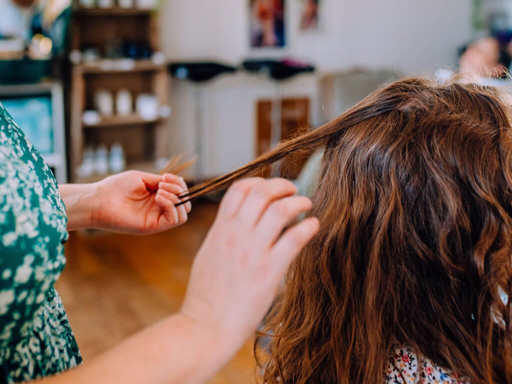 coiffeuse mily cuts qui touche les cheveux d'une cliente pour poser un diagnostic